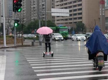 大妹纸,你也太肆意了!雨天打粉伞,踩个“风火轮”。